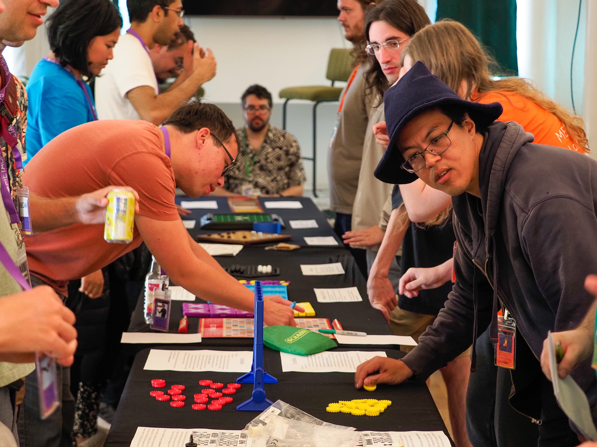 A crowd leaning over a long table of abstract games during the board game round robin